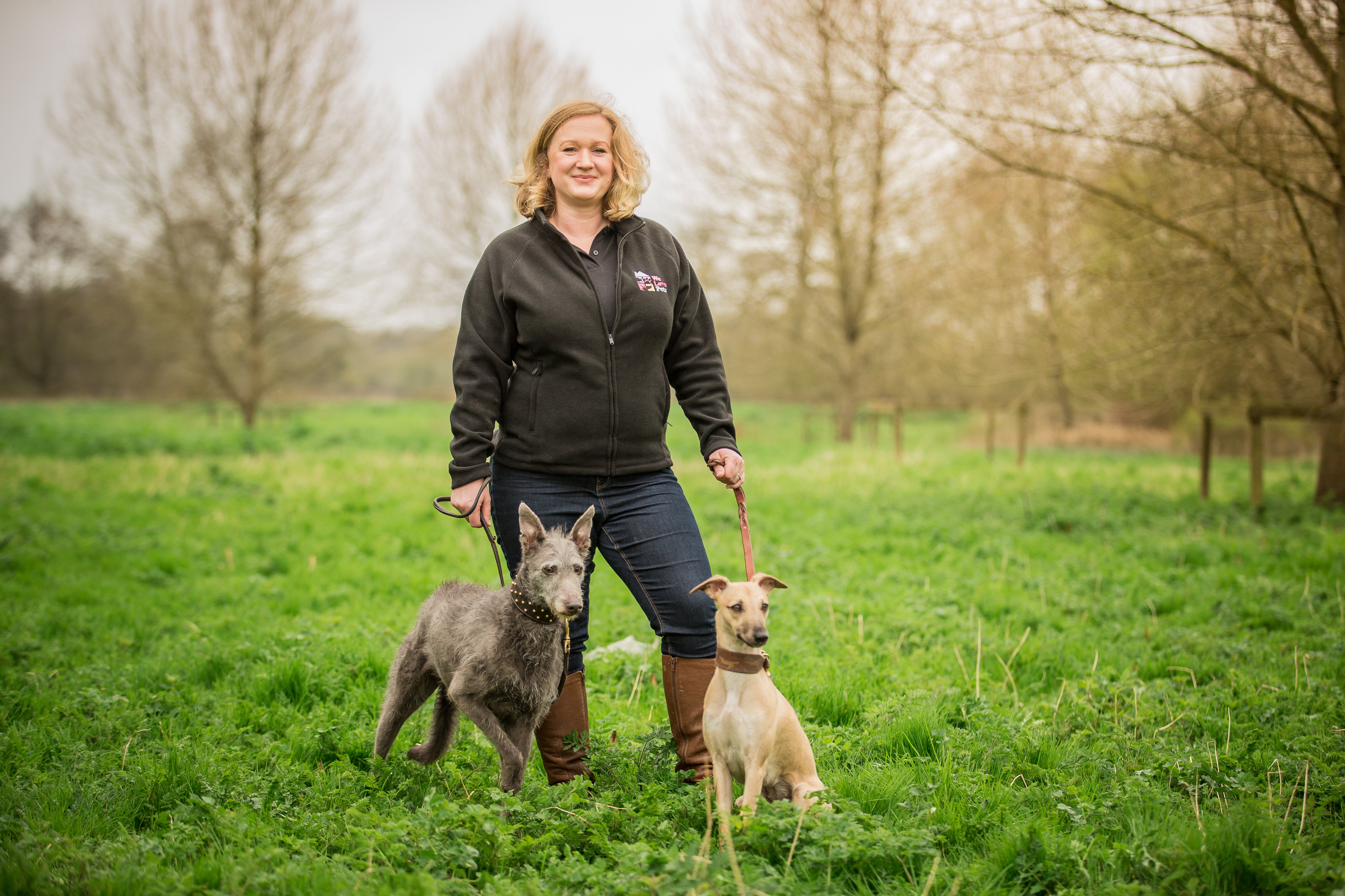 We Love Pets franchisee in a field with two dogs on leads